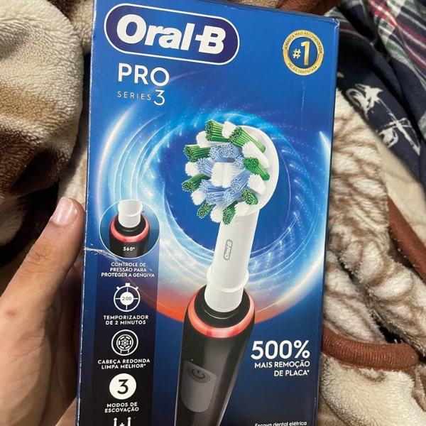 Pessoa segurando a embalagem da escova elétrica Oral-B PRO Series 3 com destaques em 500% de remoção de placa