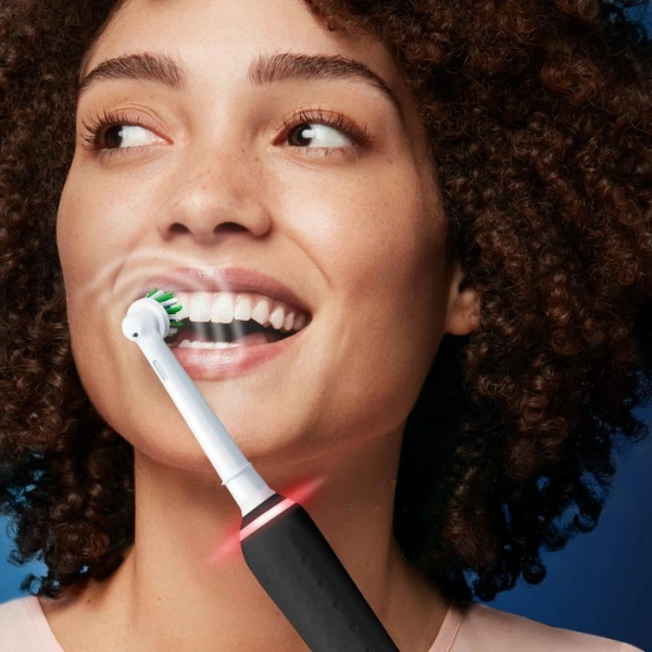 Mulher escovando os dentes com escova elétrica Oral-B PRO Series 3 ativada com luz vermelha