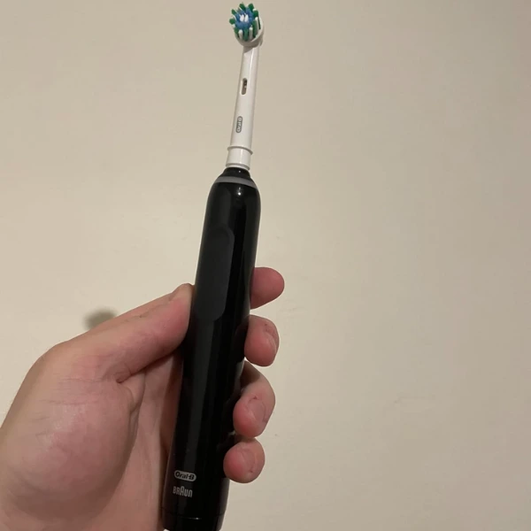 Pessoa segurando a escova elétrica Oral-B PRO Series 3 na mão em fundo neutro