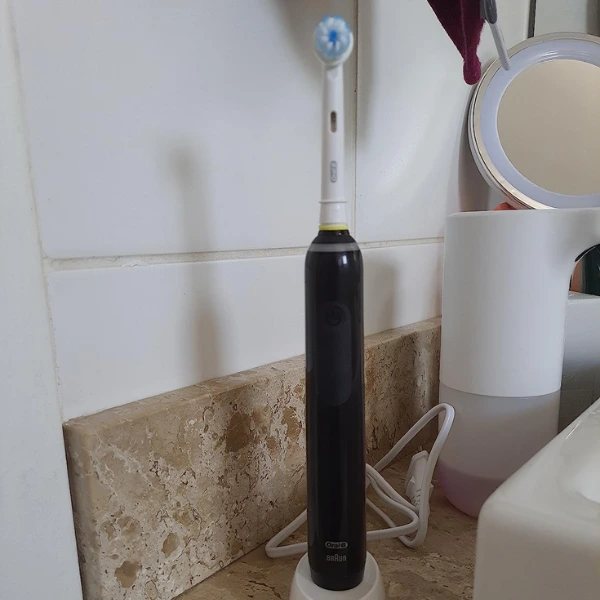 Escova elétrica Oral-B PRO Series 3 carregando sobre pia de mármore no banheiro