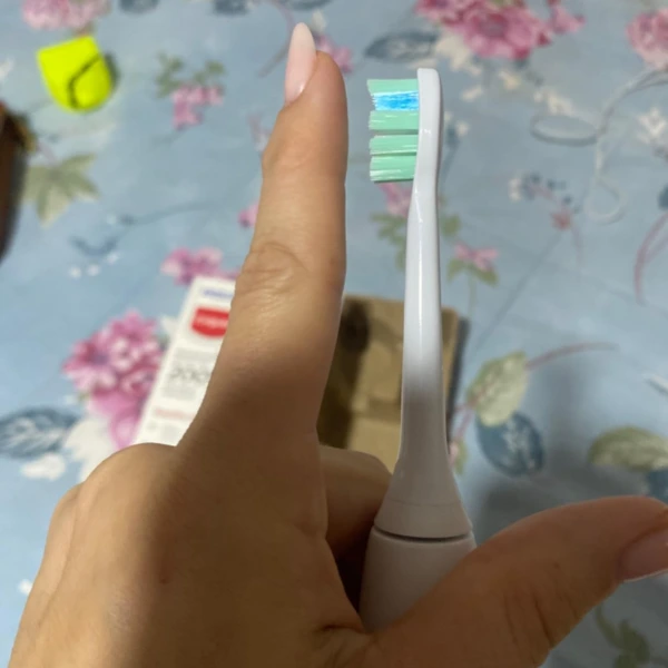 Detalhe das cerdas da escova Philips Colgate SonicPro 10 sendo comparadas ao tamanho do dedo indicador