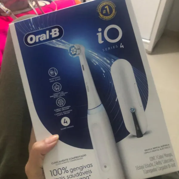 Caixa do modelo Oral-B iO Series 4 sendo segurada, com destaque para o design da escova e funcionalidades