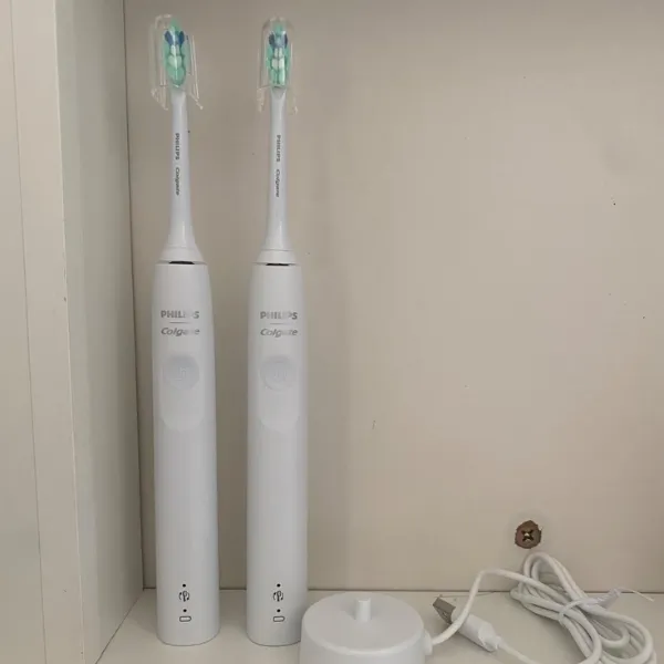 Duas escovas Philips Colgate Sonic Pro 35 lado a lado dentro de armário, com base e carregador USB