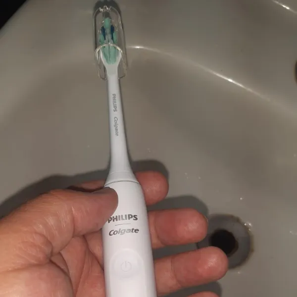 Pessoa segurando a escova Philips Colgate Sonic Pro 35 sobre pia branca