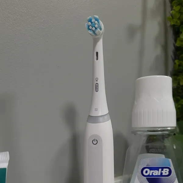 Escova elétrica Oral-B iO Series 4 em pé no banheiro, ao lado de enxaguante bucal da mesma marca