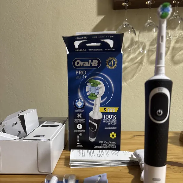 Oral-B PRO Series 1+ posicionada ao lado da embalagem do produto sobre mesa de madeira