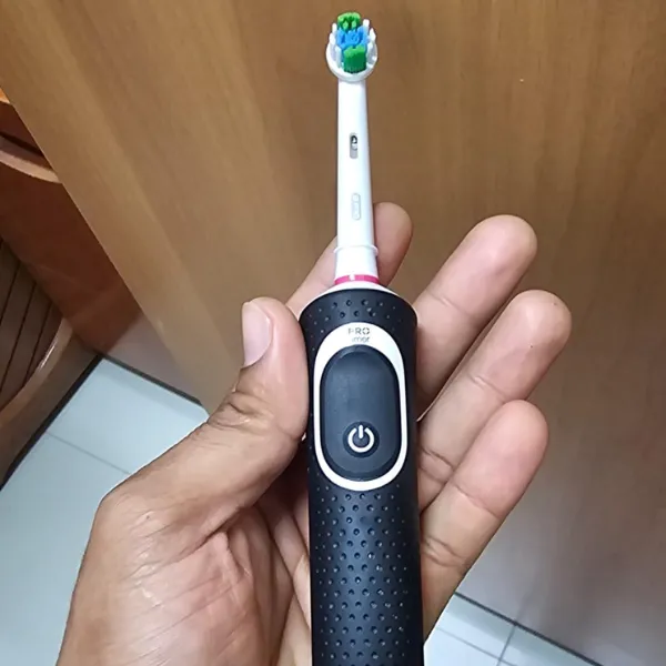 Pessoa segurando a escova elétrica Oral-B PRO Series 1+ em ambiente interno