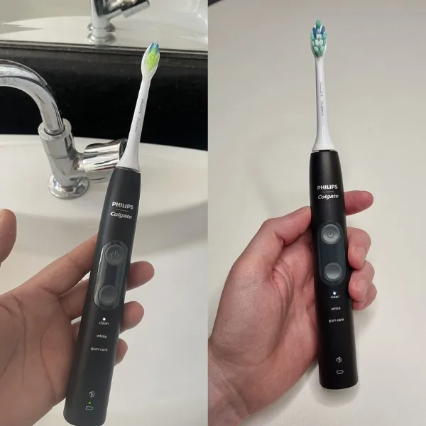 Escova elétrica Philips Colgate SonicPro 50 sendo segurada em ambientes de banheiro, com foco nas cerdas