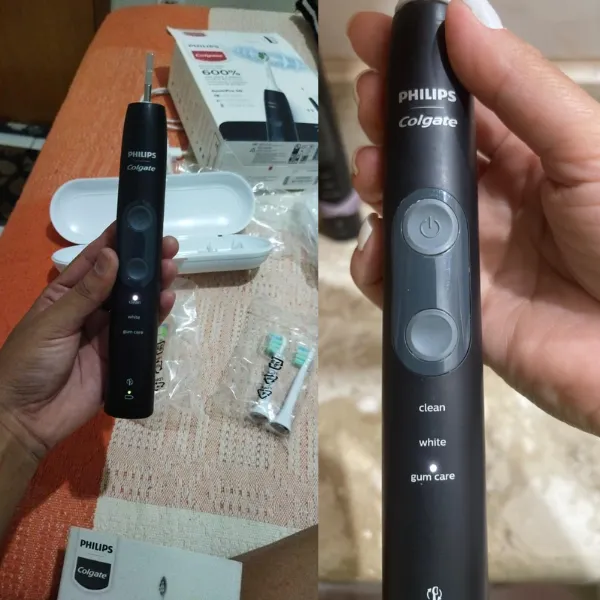 Escova Philips Colgate SonicPro 50 sendo segurada com acessórios ao fundo, incluindo refis e estojo