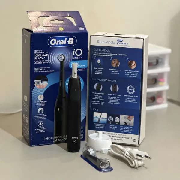 Kit completo da escova elétrica Oral-B iO Series 2 com caixa, refil, manual, carregador e acessórios sobre a mesa