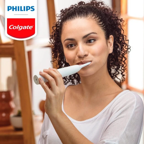 Mulher escovando os dentes com a escova elétrica Philips Colgate SonicPro 10 em ambiente iluminado
