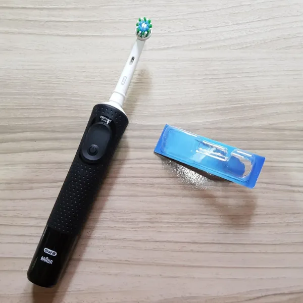 Escova elétrica Oral-B Pro Series 2 sobre superfície de madeira com refil de cabeça.